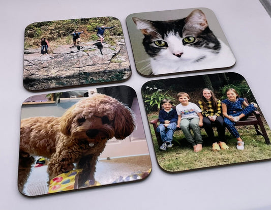 Custom coasters showing 4 different photo designs of a cat, a dog, a family photo and an adventure photo of 3 people jumping in to a river